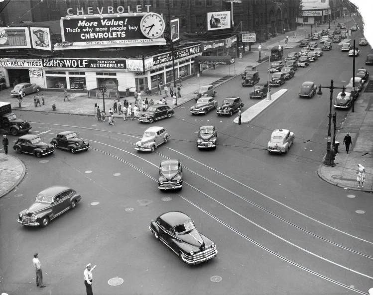 Busy Broad and Spring Garden intersection around 1948 with Elmer Harold Wolf Chevrolet dealership, Chevrolet billboard clock, trolley tracks, and a traffic officer